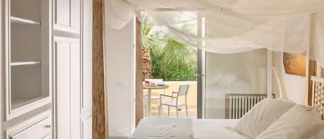 Une chambre à coucher avec un lit à baldaquin, une vue sur l’extérieur et un coin repas comprenant une table et des chaises.