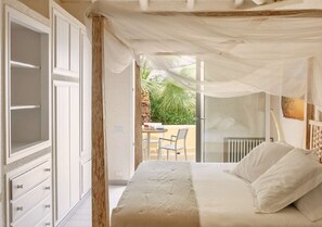 A bedroom with a canopy bed, a view of the outdoors, and a dining area with a table and chairs. - Elegant 7 Bedroom Villa, Pool and Panoramic Sea Views (Costa Saracena-Castelluccio)