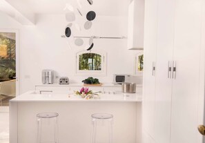A modern kitchen with a white countertop, stainless steel appliances, and a window with a view of greenery. - Elegant 7 Bedroom Villa, Pool and Panoramic Sea Views (Costa Saracena-Castelluccio)