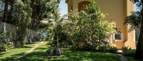 A well-maintained garden with a pathway leading to a building with a tiled roof and a small window.