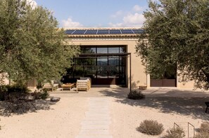A modern building with a solar panel roof, a glass entrance, and outdoor furniture. - 4BR Villa in Noto, Heated Pool (Noto)