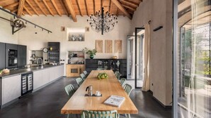 A modern kitchen with a wooden ceiling, a dining area with a long table, and a view through a glass door. - Elegant 4 Bedroom Private Pool Villa in Acireale (Acireale)