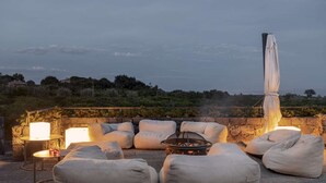 An outdoor seating area with stone walls, cushions, a fire pit, and a view of the landscape. - Elegant 4 Bedroom Private Pool Villa in Acireale (Acireale)