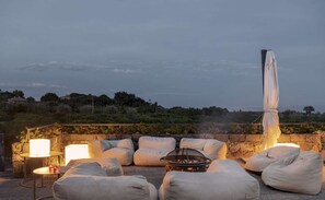 An outdoor seating area with stone walls, cushions, a fire pit, and a view of the landscape. - Elegant 4 Bedroom Private Pool Villa in Acireale (Acireale)