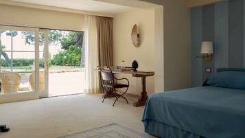 A hotel room with a bed, a desk, a chair, a lamp, and a view of the outdoors.