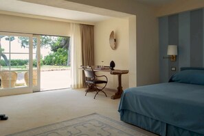 Ein Hotelzimmer mit Bett, Schreibtisch, Stuhl, Lampe und Blick ins Freie.