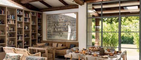 A cozy reading nook with bookshelves, a comfortable sofa, and a dining area with a table set for a meal.