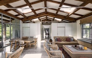 A spacious interior with a high ceiling, a dining area with a table and chairs, a sofa, and a window with a view. - Large Orbetello Villa with Private Pool (Orbetello)