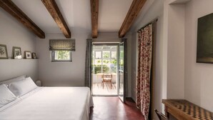 A bedroom with a bed, a window, a door leading to an outdoor area, and a wooden bench. - Large Orbetello Villa with Private Pool (Orbetello)