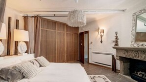 Ein Schlafzimmer mit Bett, Nachttischlampen, einer Wand aus Holzlatten, einem Kamin und einem Spiegel.