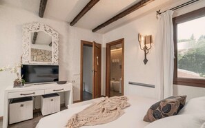 Une chambre à coucher avec un lit, une commode, un téléviseur, un miroir et une fenêtre avec des rideaux.