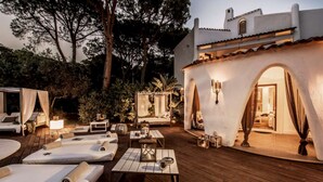 Eine gut beleuchtete Außenpatio-Terrasse mit Liegestühlen, Tischen und einem überdachten Sitzbereich.