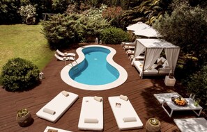 A swimming pool with a wavy edge, surrounded by lounge chairs and a canopy. - Sardinia Dream Getaway: 4BR Villa with Pool & Garden (Santa Margherita di Pula)