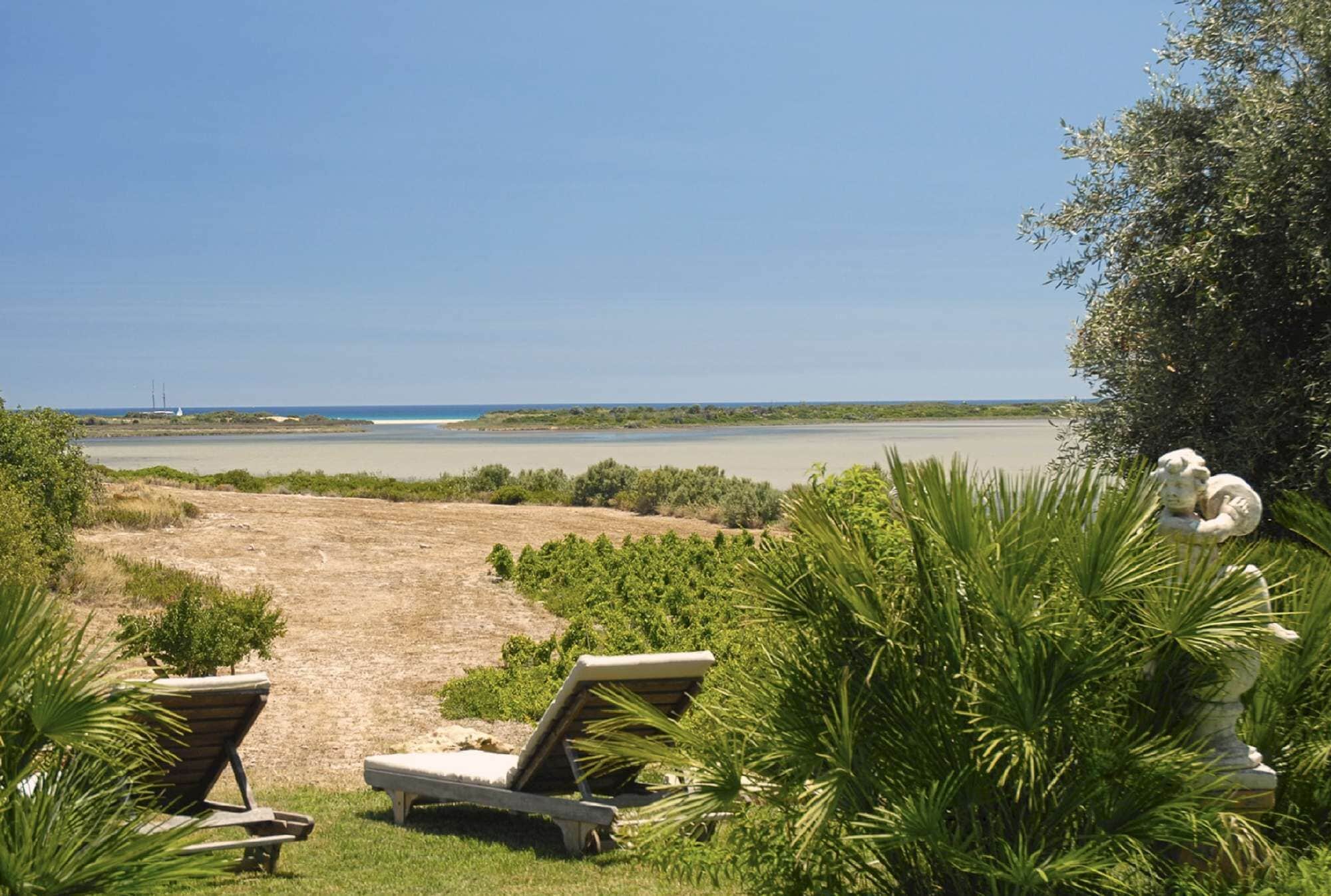 A beach view with lounge chairs and a statue.