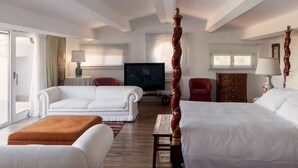 A hotel room with a four-poster bed, a television, a red armchair, and a wooden cabinet. - Stunning 7BR Villa in Noto with Sea View (Noto)