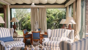 A sunlit room with striped sofas, a glass coffee table, and a dining table with chairs. - Stunning 7BR Villa in Noto with Sea View (Noto)