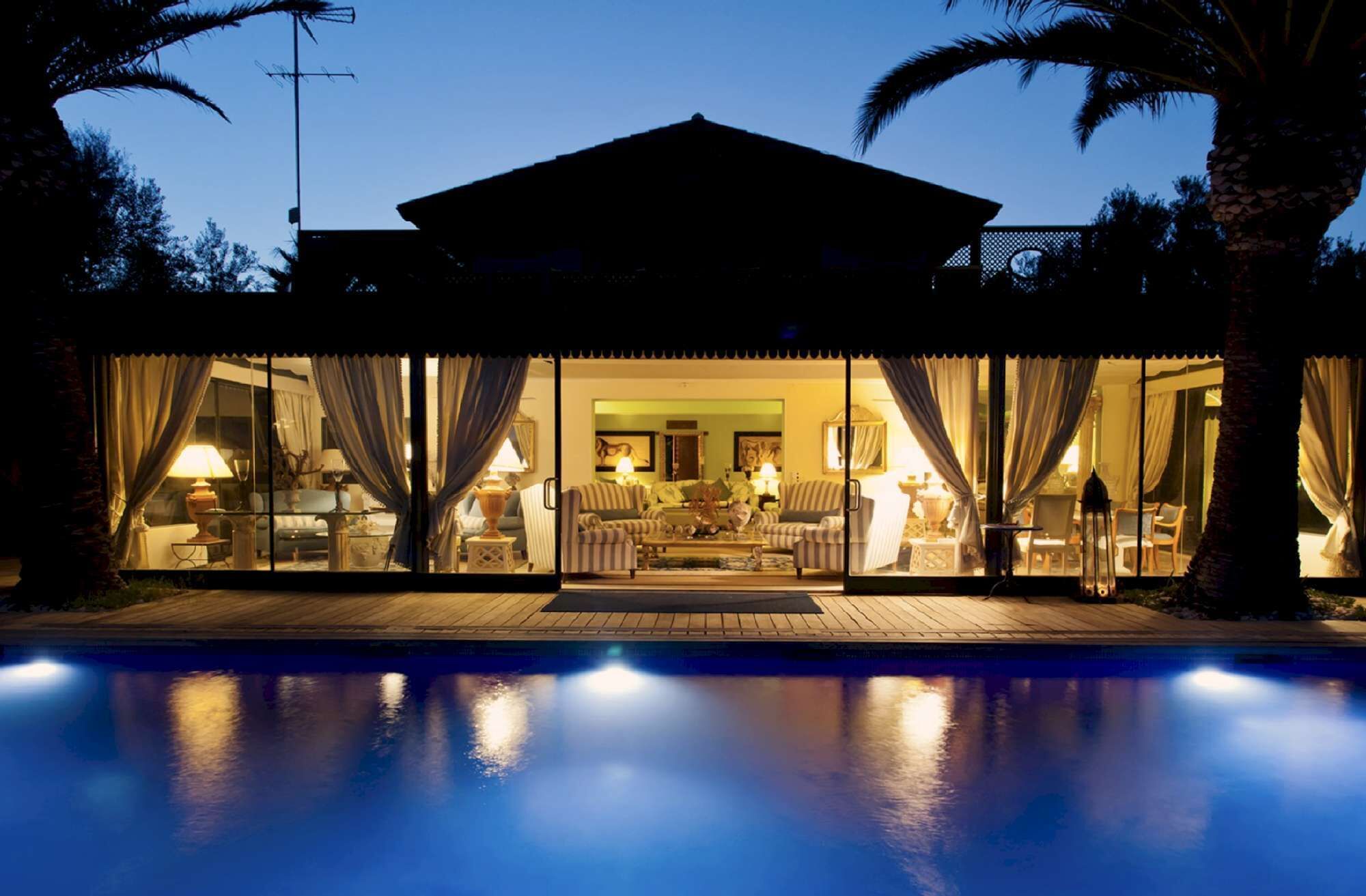 Una casa con piscina, ventanas amplias y cortinas.