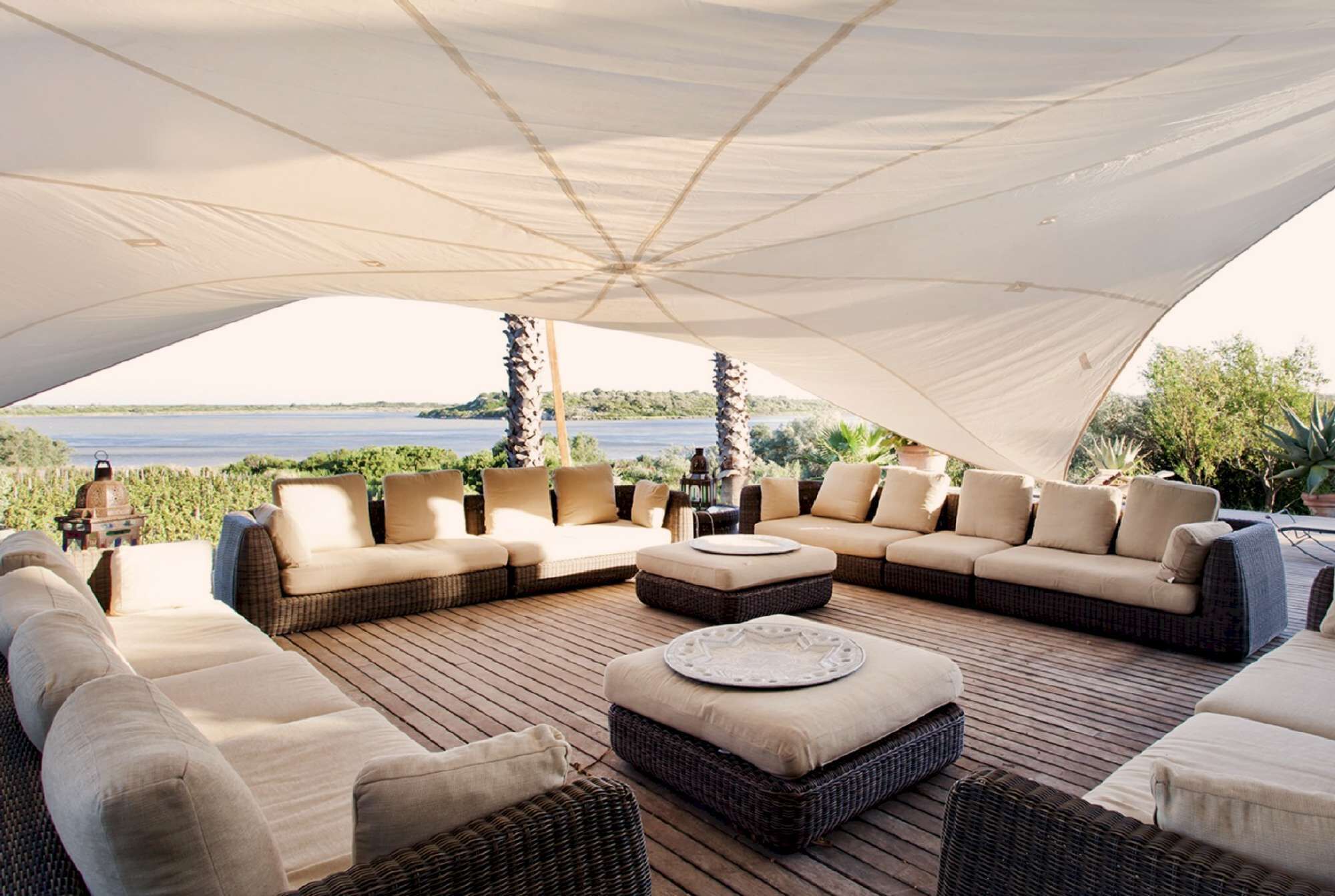 A covered outdoor seating area with wicker furniture and a view of the water.