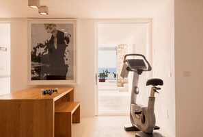 Ein modernes Zimmer mit einer hölzernen Bank, einem Heimtrainer und einem großen abstrakten Gemälde.
