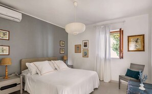 A bedroom with a bed, nightstand, lamp, and wall art. - Elegant 5 Bedroom Villa,  Pool and Panoramic Sea Views (Costa Saracena-Castelluccio)