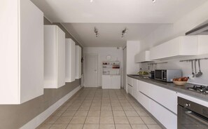 Eine moderne Küche mit weißen Schränken, einer Mikrowelle und einem Gasherd.