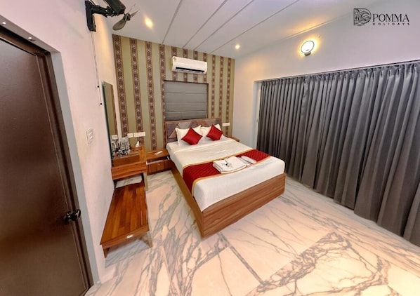 A hotel room with a bed, a desk, a mirror, an air conditioning unit, and a curtain.