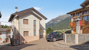 Un edificio con un coche estacionado adelante, una escalera y una montaña al fondo.