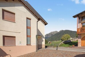 A building with a tiled entrance, a visible window, and a mountain in the background.