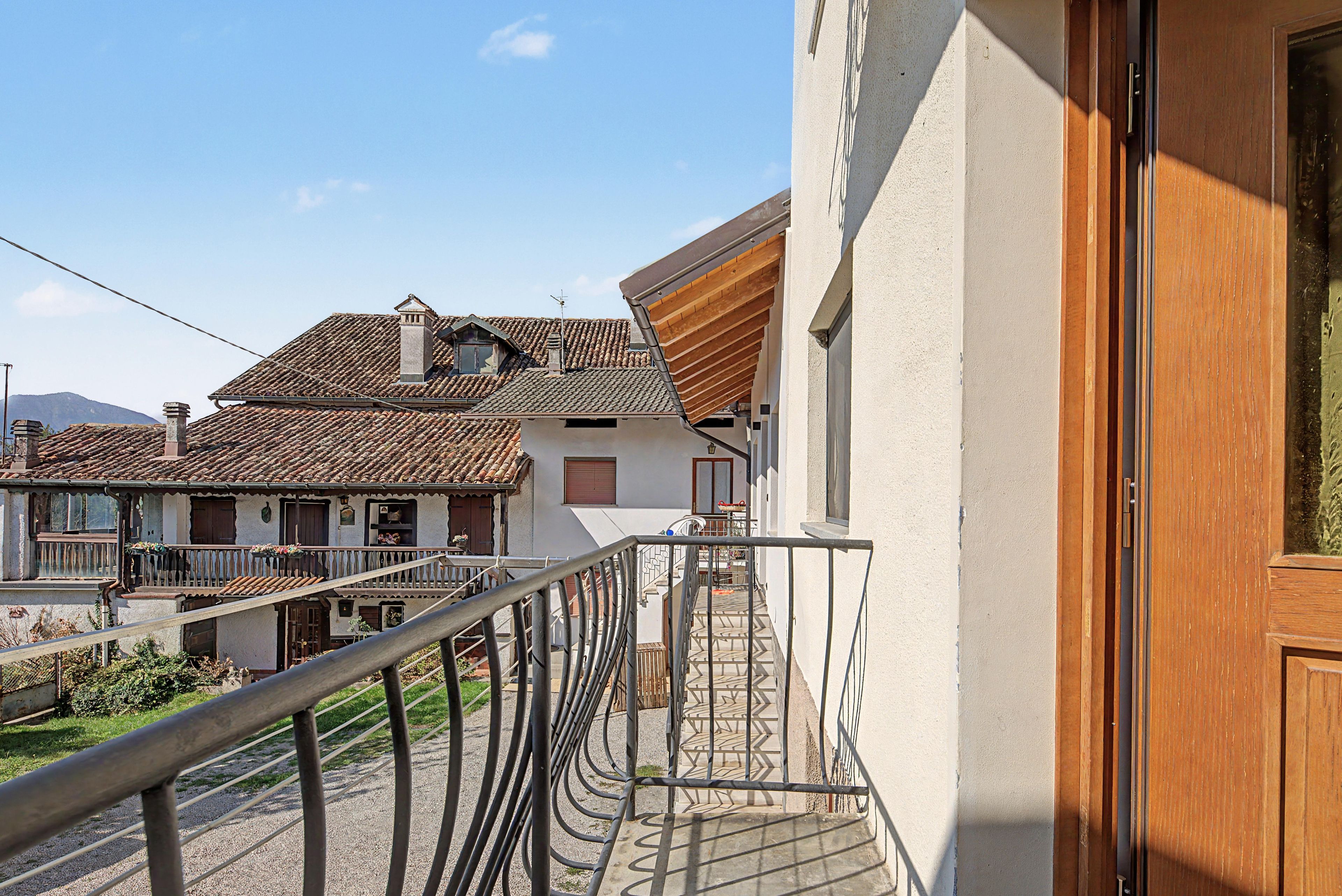 Un edificio residenziale con un balcone, una scala e vista sulle case vicine.