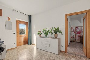 A hallway with a wooden door, a mirror, a potted plant, and a small table with a floral design.