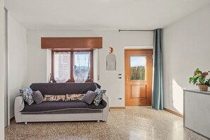 A room with a sofa, a door, and a window.