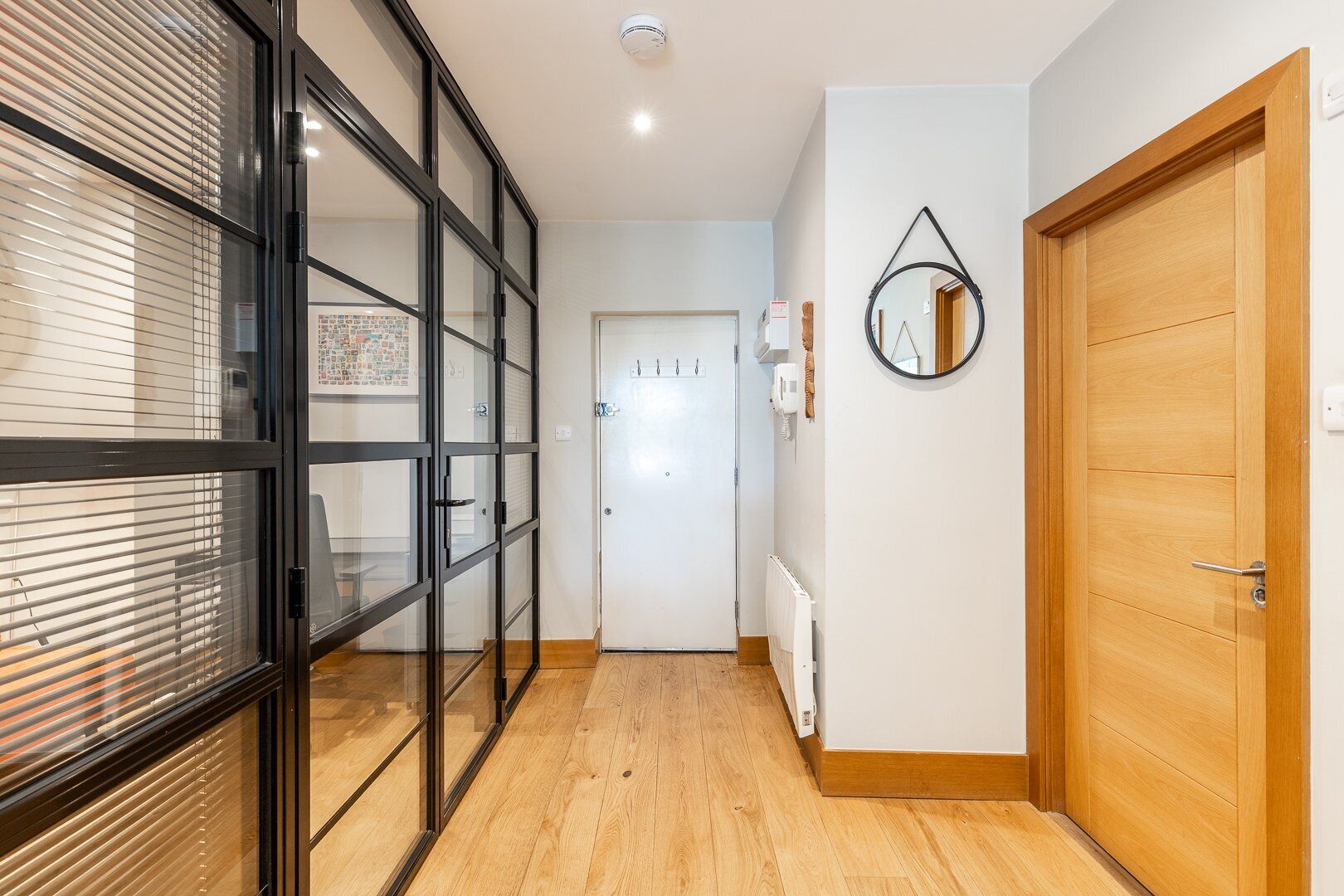 A hallway with a glass door, a wooden door, and a radiator on the wall.