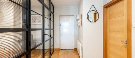 Un pasillo con una puerta de vidrio, una puerta de madera y un radiador en la pared.
