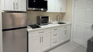A modern kitchen with white cabinetry, stainless steel appliances, and a built-in oven. - Paradise at Sunset Shore 1-bedroom apartment with the Huntington Beach breeze (Huntington Beach)