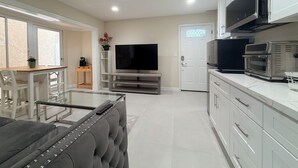 A modern kitchen with a flat-screen TV, built-in oven, and white cabinetry. - Paradise at Sunset Shore 1-bedroom apartment with the Huntington Beach breeze (Huntington Beach)