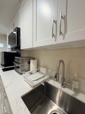 A modern kitchen with white cabinets, stainless steel appliances, and a built-in dishwasher. - Paradise at Sunset Shore 1-bedroom apartment with the Huntington Beach breeze (Huntington Beach)