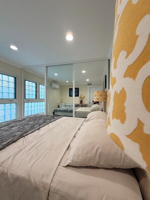 Ein Schlafzimmer mit einem Bett, einem Spiegel und einem Fenster.