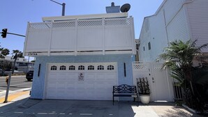 A two-story building with a garage door, a street lamp, and a satellite dish on the roof. - Paradise at Sunset Shore 1-bedroom apartment with the Huntington Beach breeze (Huntington Beach)