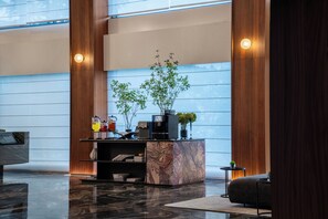 Un vestíbulo moderno con una recepción, una máquina de café y un área de descanso.