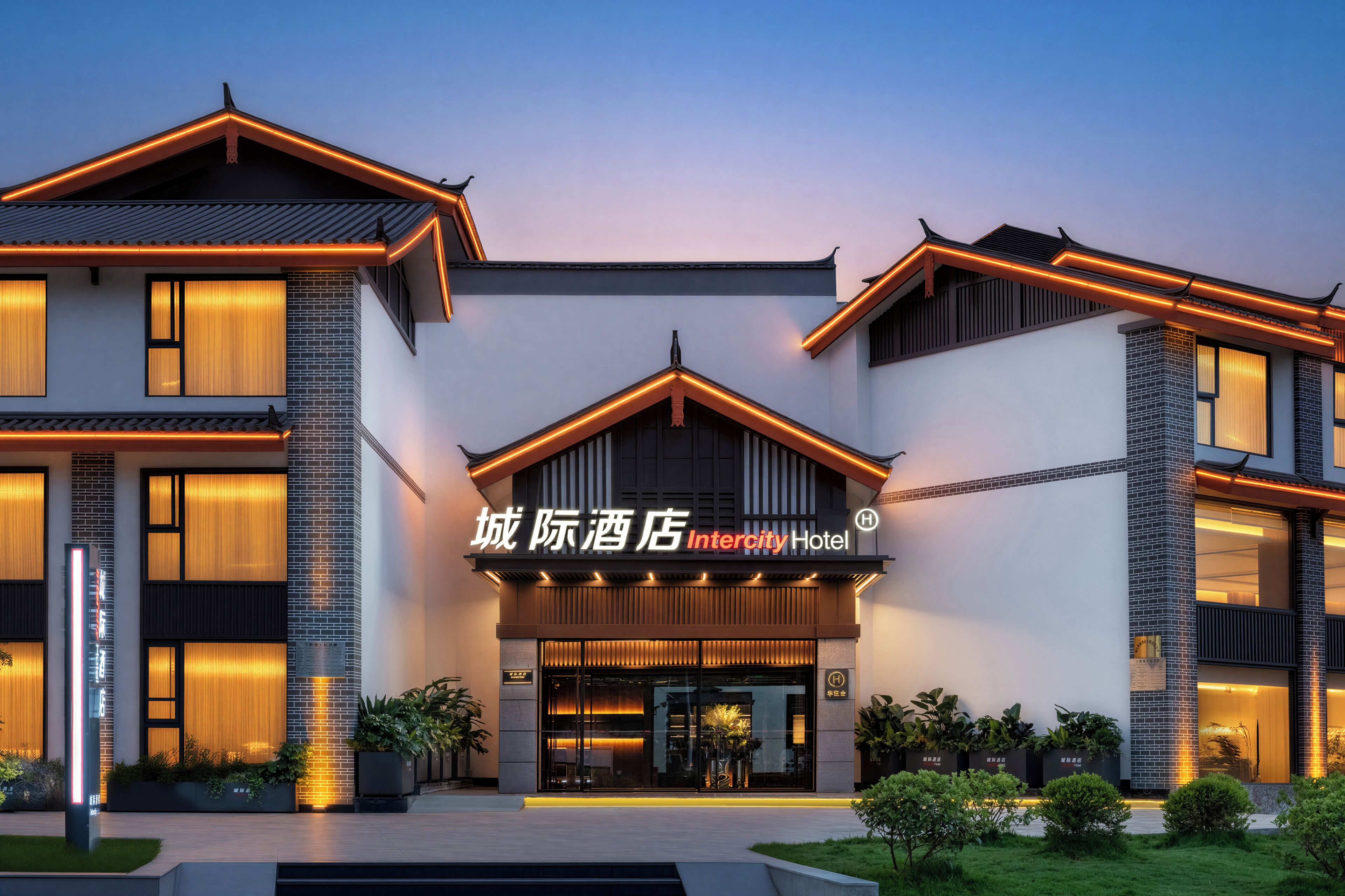 A modern hotel with a prominent entrance, large windows, and a well-lit facade.
