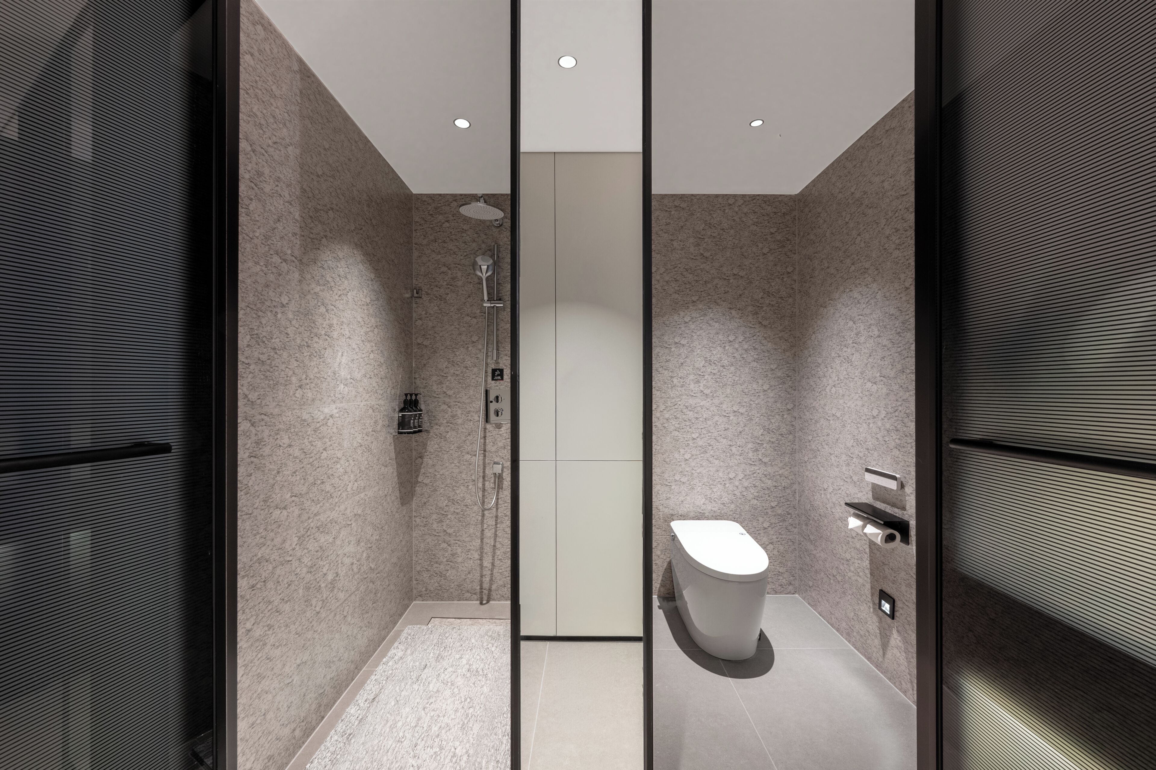 A modern bathroom with a shower, toilet, and storage cabinets.