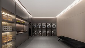 Uma lavanderia moderna com várias máquinas de lavar, prateleiras com produtos de higiene e um banco.