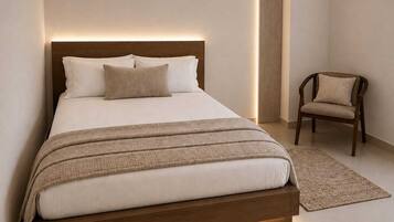 A modern bedroom with a bed, a chair, and a bedside table.