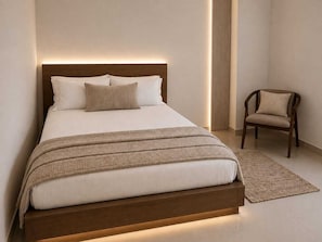 A modern bedroom with a bed, a chair, and a bedside table.