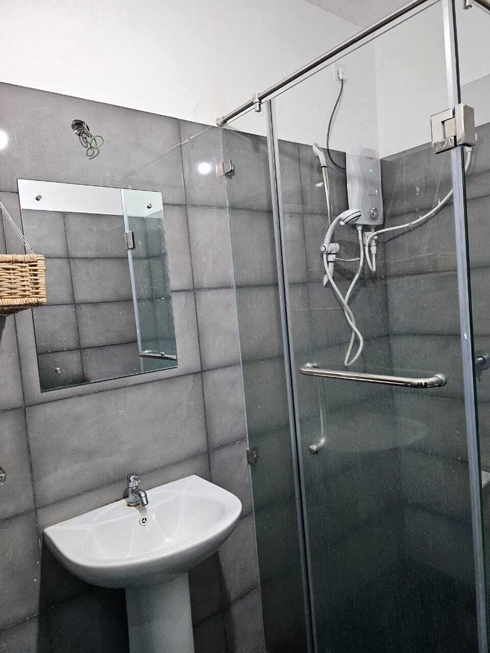 Ein Badezimmer mit einer Duschkabine aus Glas, einem weißen Waschbecken und einem Spiegel.