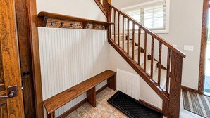 Eine Holztreppe mit Geländer, einer Tür, einer Sitzbank und einem Heizkörper.