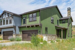 A two-story house with a green exterior and a stone chimney. - Hot Tub, Mtn & Lake Views! Group Abode in Daniel (Daniel)