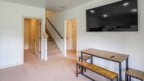 A hallway with a staircase, a dining area with a table and bench, and a large black artwork on the wall. - Hot Tub, Mtn & Lake Views! Group Abode in Daniel (Daniel)
