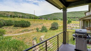 A balcony with a grill, overlooking a grassy landscape with houses in the distance. - Hot Tub, Mtn & Lake Views! Group Abode in Daniel (Daniel)