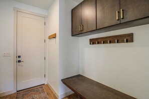 Un couloir avec une porte blanche, un banc en bois et un meuble en bois doté de poignées.